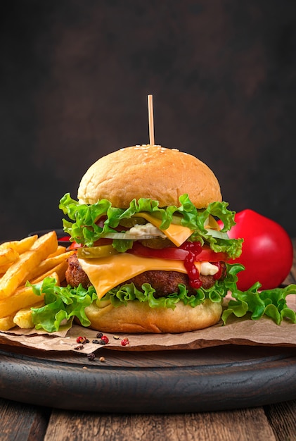 Hamburguesa casera con queso de ternera, tomate y pepinos encurtidos closeup sobre una pared marrón