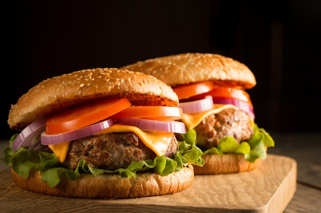 Hamburguesa casera con ternera, cebolla, tomate, lechuga y queso. Hamburguesa fresca de cerca en la mesa rústica de madera con papas fritas, cerveza y patatas fritas. Hamburguesa con queso.