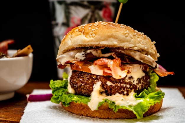 Hamburguesa casera de ternera con lechuga, tomate, champiñones y queso sobre una tabla de madera con fondo negro Vista normal Copiar texto Concepto de comida rápida