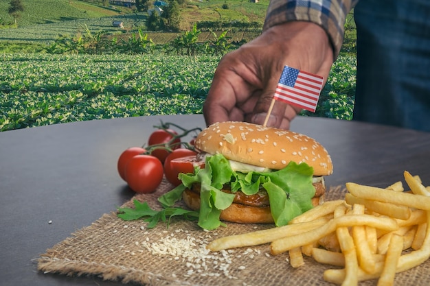 Foto la hamburguesa casera con verduras frescas patatas fritas carne de res cebolla tomate banderas estadounidenses