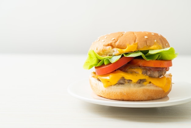 Hamburguesa de cerdo con queso en la placa blanca.