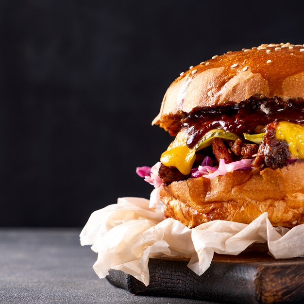 Hamburguesa de cerdo tirada con cebolla, repollo y queso sobre tabla de madera