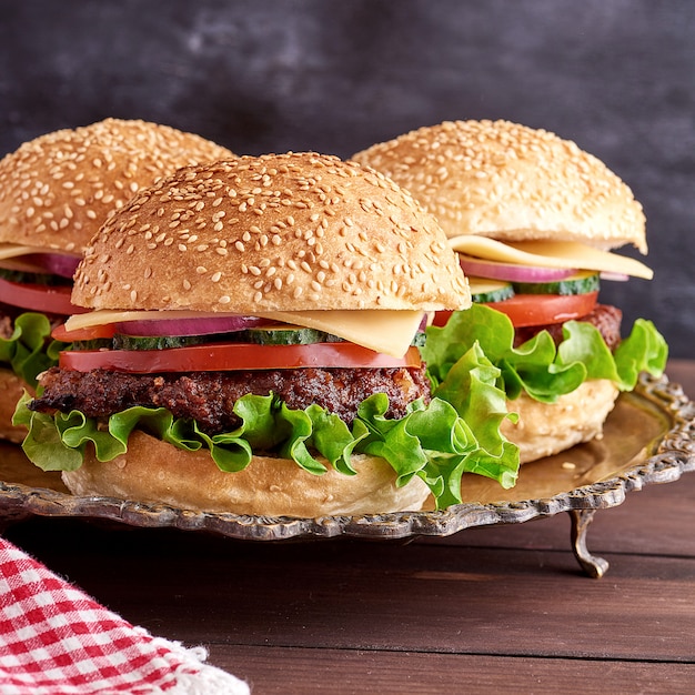 Hamburguesa con chuleta frita, queso y verduras en un bollo de harina de trigo redondo