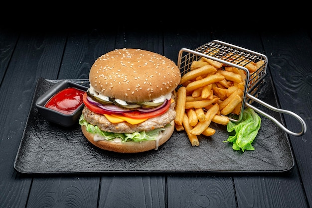 Hamburguesa con chuleta de pollo y papas fritas sobre un fondo oscuro