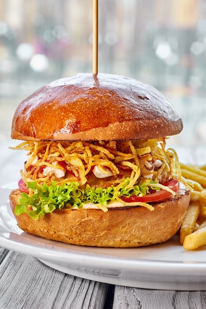 Hamburguesa con chuleta de pollo, queso, papas fritas, tomate, ensalada, salsa y salsa de tomate