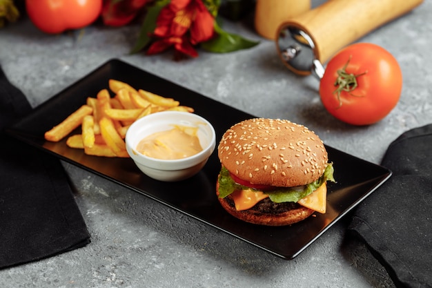 Hamburguesa con chuleta, queso y tomates. Con papas fritas y salsa de hamburguesa