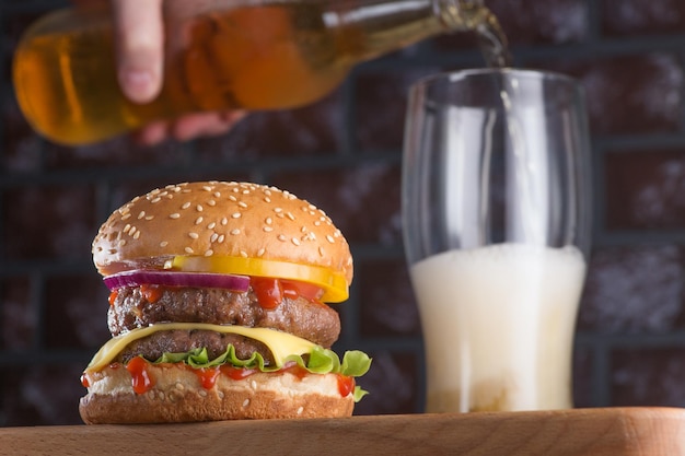 Una hamburguesa clásica con chuleta y un vaso de cerveza fría. Comida tradicional americana, cerveza y snacks.