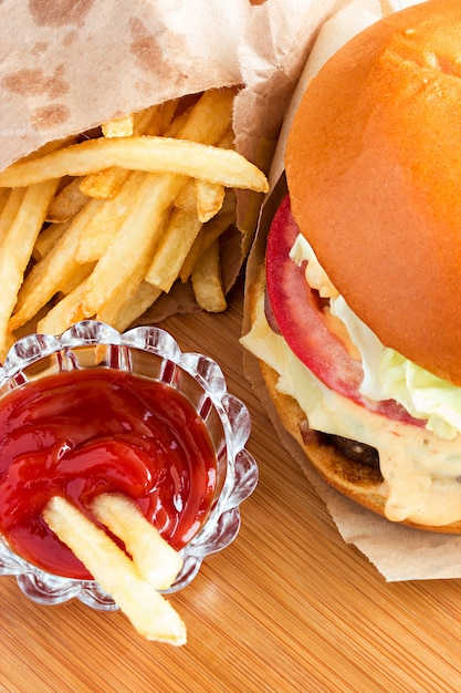 Hamburguesa clásica fresca con papas fritas y salsa de tomate sobre fondo de madera