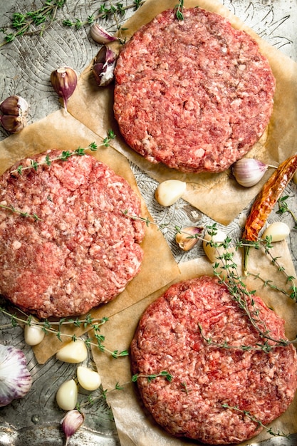 Hamburguesa cruda con ajo y especias en una bandeja de acero