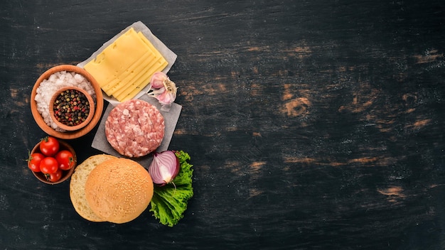 Hamburguesa cruda Cocinar una hamburguesa con carne Sobre un fondo de madera negra Vista superior Espacio de copia libre