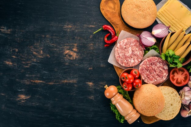 Hamburguesa cruda Cocinar una hamburguesa con carne Sobre un fondo de madera negra Vista superior Espacio de copia libre