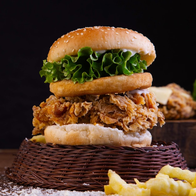 una hamburguesa crujiente con lechuga y patata de pollo en la parte superior de una canasta
