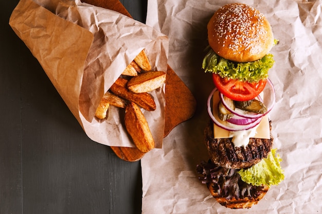 Hamburguesa descompuesta en sus componentes en papel kraft sobre una mesa de madera. paquete de chips.