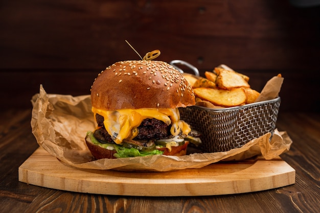 Hamburguesa doble con papas fritas sobre tabla de madera