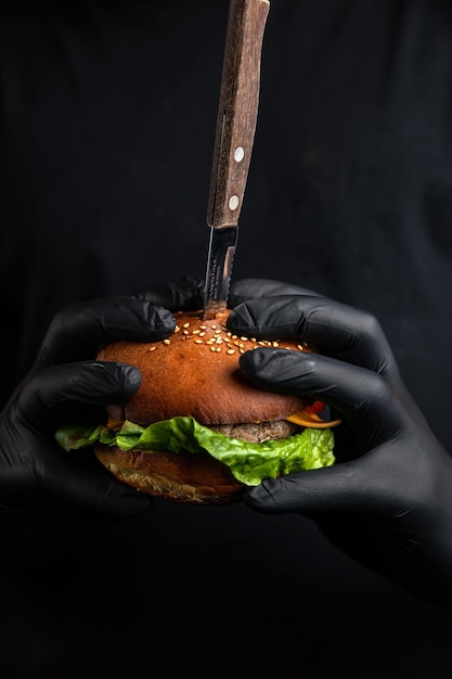 hamburguesa con ensalada de chuleta de queso tomate en las manos