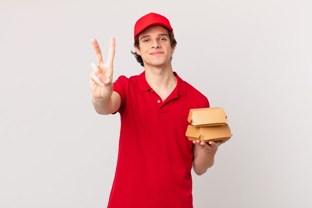 Hamburguesa entrega a hombre sonriendo y mirando amigable, mostrando el número dos