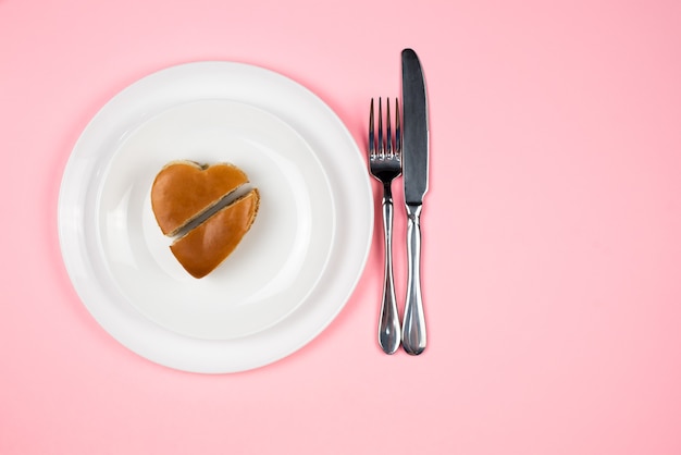 Una hamburguesa en forma de corazón abierta en un plato blanco. La vista desde arriba. Concepto de San Valentín.