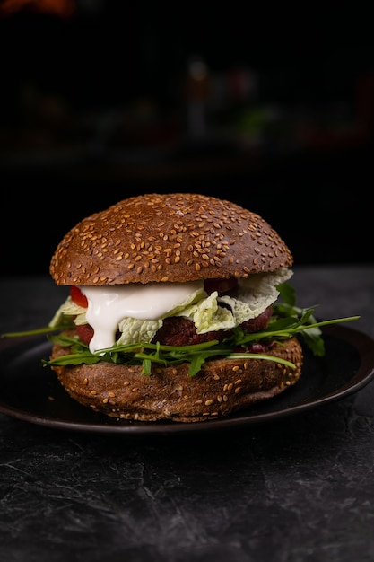 Hamburguesa fresca con carne y verduras veganas, espolvoreada con semillas de sésamo