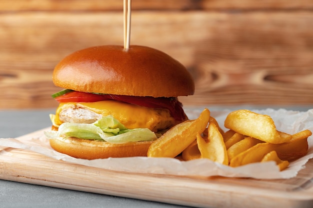 Hamburguesa fresca y gajos de patata sobre fondo de madera gris