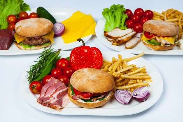 Hamburguesa fresca en plato con verduras y papas fritas