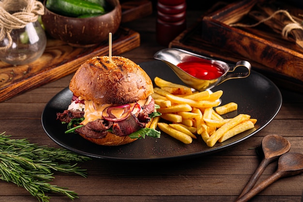 Hamburguesa gourmet con carne de vacuno y papas fritas en la mesa de madera