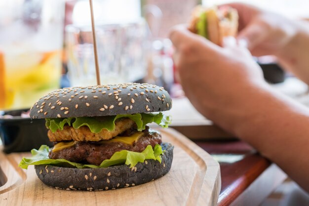 Hamburguesa gourmet negra con carne de res, queso cheddar, mermelada de cebolla y hash brown