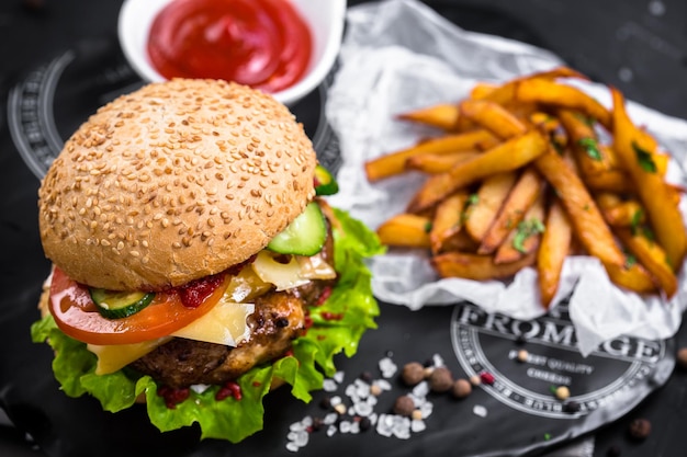 hamburguesa grande con chuleta de carne, con salsa de ketchup roja en plato blanco, tazón, papas fritas o idaho,