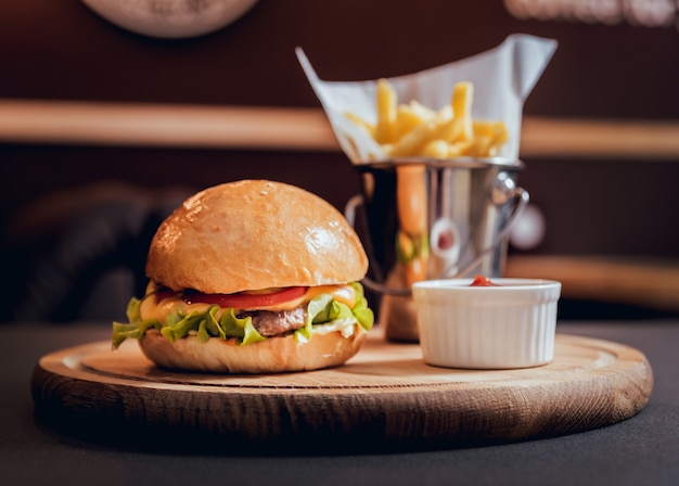 Hamburguesa grande y sabrosa con fuegos en el escritorio de madera