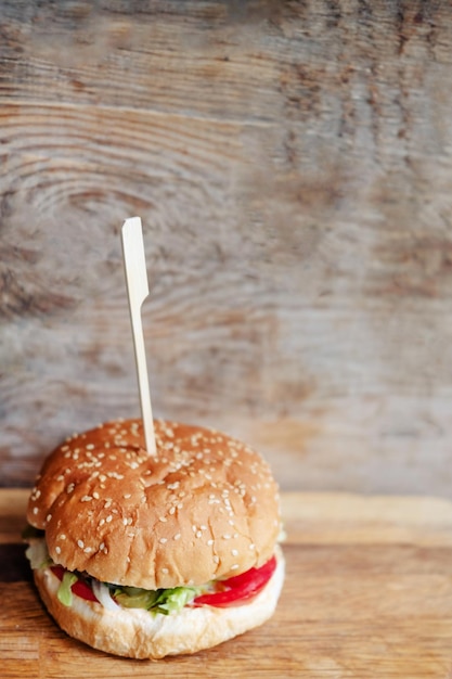 Hamburguesa grande de ternera con bollos con semillas de sésamo sobre fondo de madera de cerca