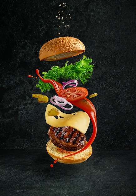 Hamburguesa con ingredientes flotantes en un fondo oscuro