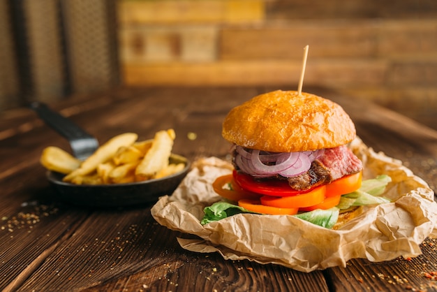 Hamburguesa de jugo con bistec fresco en primer plano de la mesa de madera, nadie. Hamburguesa con bistec, preparación de alimentos, cocinar