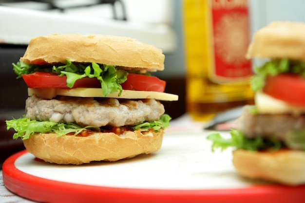 Hamburguesa con jugosa chuleta de queso y verduras frescas en el tablero Cocinar hamburguesa en la cocina casera Primer plano