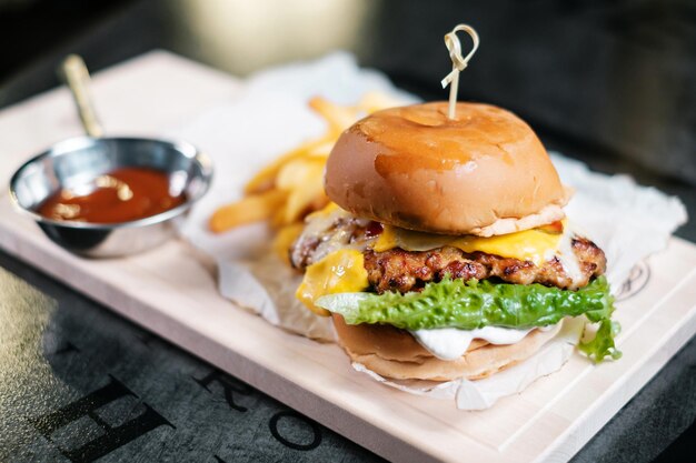 Hamburguesa jugosa con papas fritas en tablero de madera