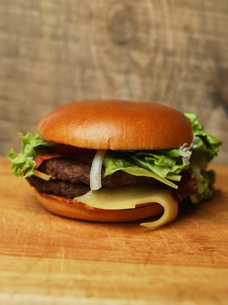 hamburguesa jugosa sobre una tabla de madera hamburguesa espolvoreada con semillas de sésamo sobre un fondo de madera