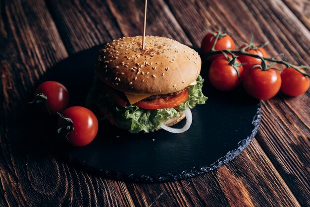 Una hamburguesa con lechuga, tomate y cebolla en un plato negro.