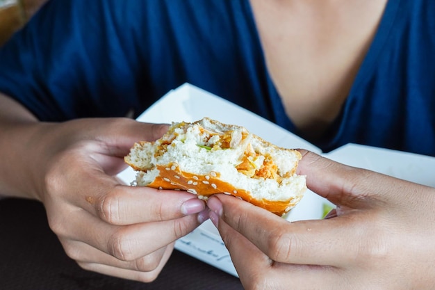 Hamburguesa en la mano del niño niño hambriento sosteniendo una hamburguesa con queso parcialmente mordida