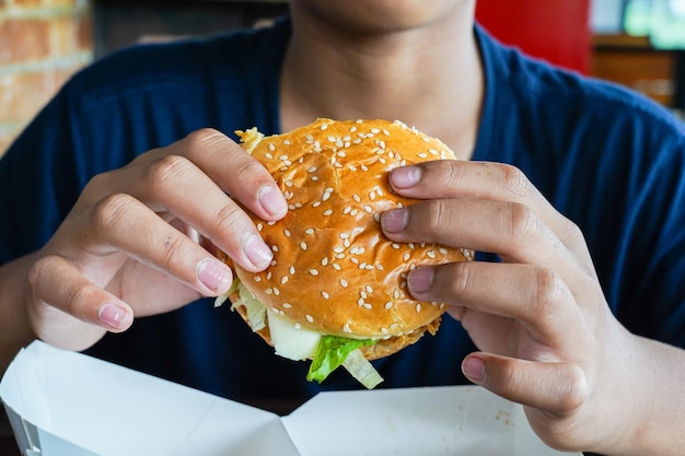 Hamburguesa en la mano de un niño, un niño hambriento sostiene una hamburguesa con queso antes de comerla, copia espacio