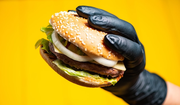 hamburguesa en manos con plumas sobre un amarillo