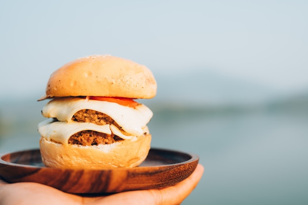 Foto hamburguesa mientras acampa en un campamento salvaje, cocina de campamento en la orilla del lago.