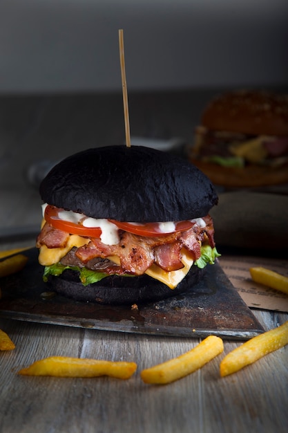 Hamburguesa negra con carne en tablero redondo de madera con hacha