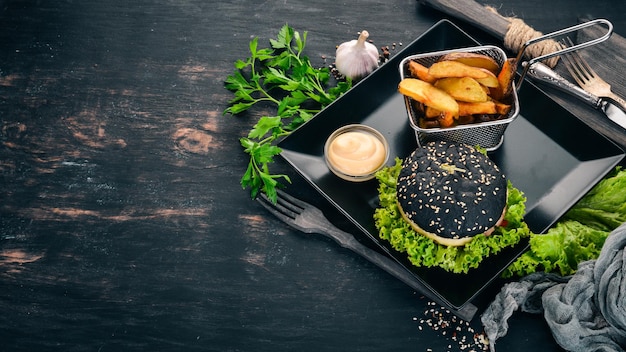 Hamburguesa negra con cebolla de carne y lechuga Sobre un fondo de madera Vista superior Espacio de copia