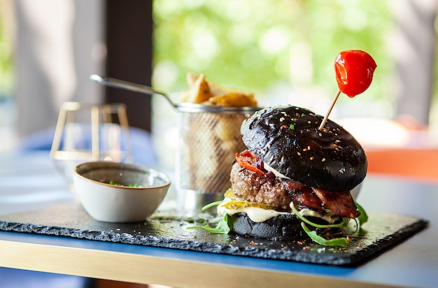 Hamburguesa negra elaborada por el chef con papas fritas en restaurante