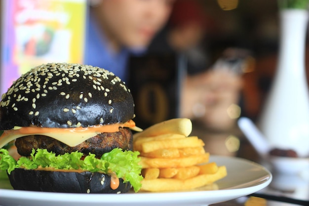 Foto hamburguesa negra con fondo de papas fritas