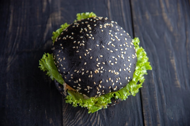 Hamburguesa negra gourmet con salsa picante en mesa de madera y fondo negro. enfoque suave. enfoque selectivo