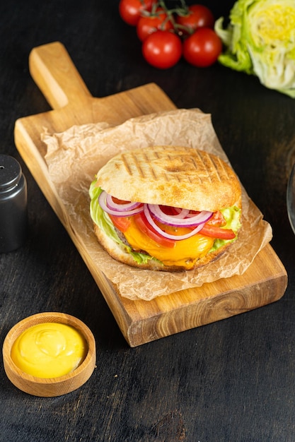 Hamburguesa en pan de pita con verduras de carne a la parrilla y salsa en la receta del menú de la pancarta de fondo oscuro