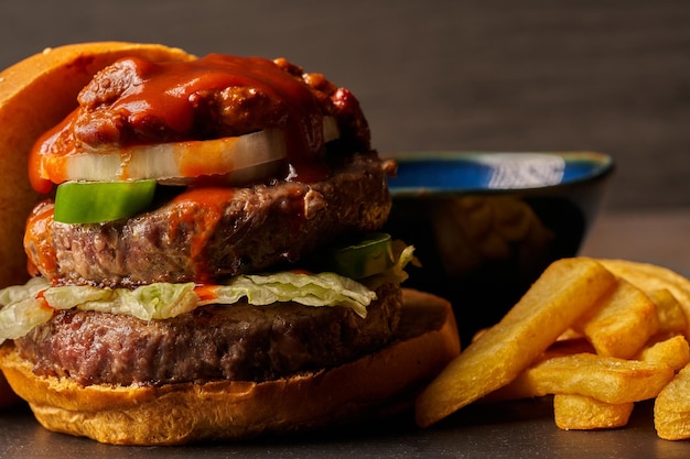 Hamburguesa con papas fritas cebolla chili con carne y jalapeños salsa barbacoa comida de estilo oscuro