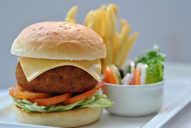 Hamburguesa con papas fritas y ensalada, hamburguesa artesanal y papas fritas en una mesa de madera aislada en blanco