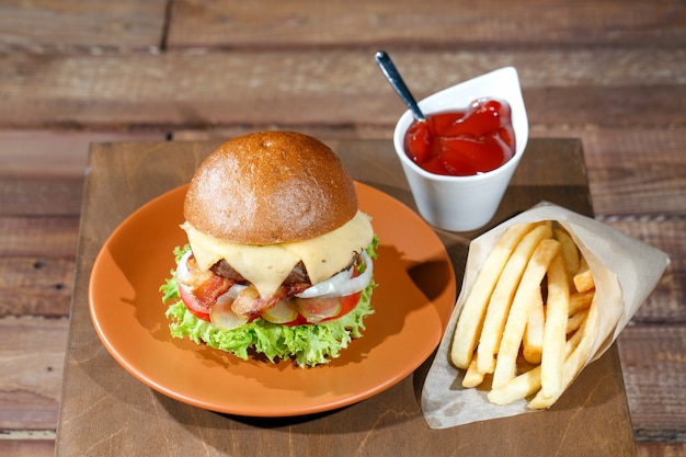 Hamburguesa y papas fritas en la mesa de madera.