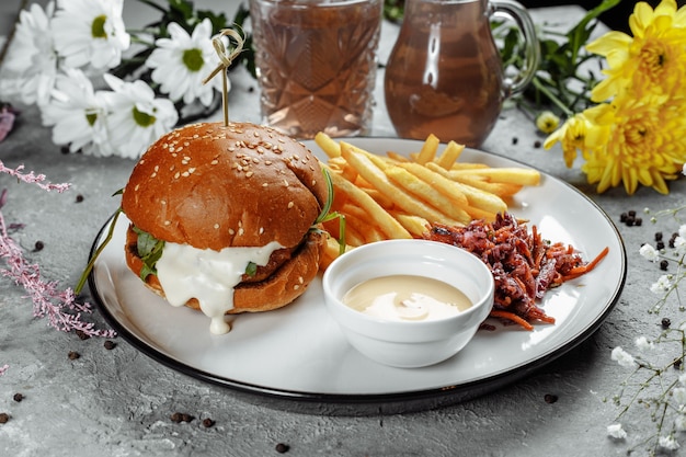 Hamburguesa con papas fritas y salsa en una placa blanca.