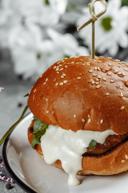 Hamburguesa con papas fritas y salsa en un plato blanco.